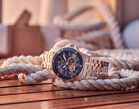 Bulova Marine Star automatic watch with blue dial and open-heart feature, displayed on nautical rope in warm light.